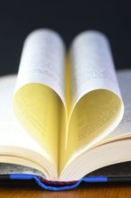 vertical heart shaped book pages showing spine ,selective focus on a black background concept of the love of reading