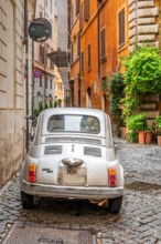 Old classic Fiat 500 car parked in a cobbled street of Rome, Lazio, Italy