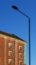 A classic street lantern embraces a stone building with bricks, against the background of the blue sky, Greenock, Scotland