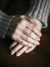Close up of senior woman hands on table. Dramatic photography