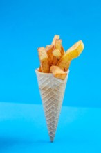 French fries bouquet in a ice cream cone on blue background. Fast food, street food concept.