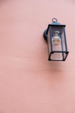 Old lantern with a white lamp. Wall color - Oriental Pink, Hue Red. Vintage lantern concept.