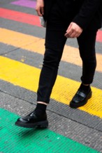 Unrecognizable legs in a rainbow crosswalk in a Gay parade. Rainbow-colored crosswalk installation. LGBTQIA