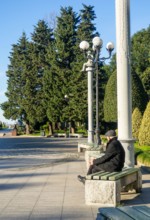A lonely man sits on a park bench. An elderly gentleman in the park. Relaxation in the park. Loneliness concept