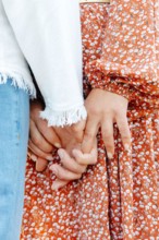 A detailed view of two individuals, their hands clasped tightly together in a strong bond, symbolizing unity and connection.