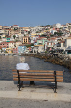 man sitting on bench in the port at parga, greece