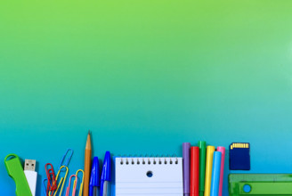 School or office supplies as a low border on a blue green background with copy space