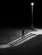 Night scene. Human figure in motion blur walking up stairs.