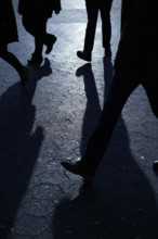 Silhouettes of unrecognizable people walking in blue night shadows