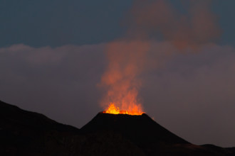 Ile de la reunion island Piton de la fournaise volcano eruption with lava flow and steam at night