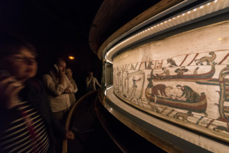 Bayeux, France. Visitorswalk past the famous tapestry (Tapisserie) of Bayeux,1000 year old carpet telling the story of the Norman conquest of England
