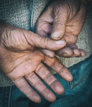 Bare senior adult hands isolated on a black background. Concept of hard worker.