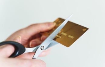 Woman cuts credit card with scissors.