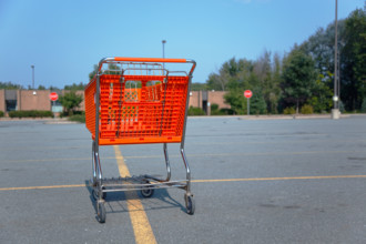 Horizontal shot of an orange shopping cart isolated on a parking lot at the mall