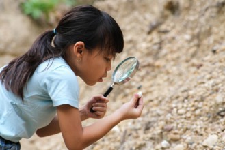 Cute little girl playing with stones and exploring with a magnifying glass. Little girl studying various natural materials. Alternative education or h