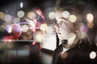 A small female child looking at a plasma ball