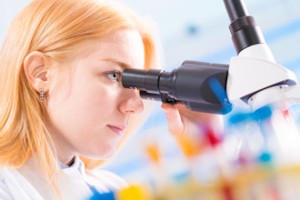 student girl looking in a microscope, science laboratory concept