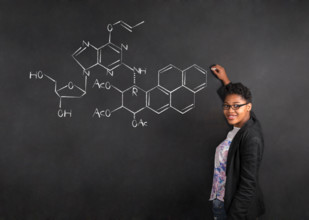South African or African American woman teacher writing science on chalk black board background