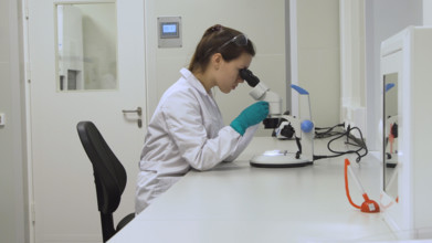 Doctor woman working a microscope. Female scientist looking through a microscope in lab. Student girl looking in a microscope, science laboratory concept