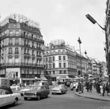 Pariser Bilder [Paris Street Life] Description: Cars and pedestrians on Boulevard Hausmann Date: 1965 Location: France, Paris Keywords: cars, buildings, street sculptures, pedestrians, shops