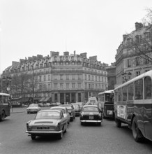 Pariser Bilder [Paris Street Life]  The Hôtel du Louvre, seen from the Avenue de l'Opera Date: 1965 Location: France, Paris Keywords: cars, buses, buildings, hotels, street images, traffic