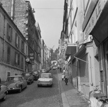 Pariser Bilder [The street life of Paris]  Rue Lepic in Montmartre, with Le Moulin de la Galette at the end of the street Annotation: Le Moulin de la Galette was a popular dance venue and figures on p...
