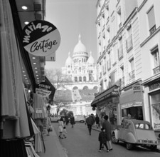 Pariser Bilder [The street life of Paris]  Shopping street with a view of the Basilique du Sacré-Coeur Annotation: The Basilique du Sacré-Coeur (1875-1914) was built on the occasion of the deaths that...