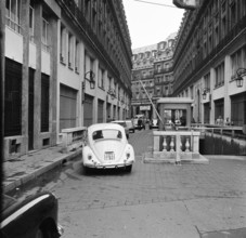 Pariser Bilder [Paris Street Life]  A Volkswagen Beetle at the barrier closing the private part of Rue Edouard VII Date: 1965 Location: France, Paris Keywords: Cars, security, controls, buildings, str...