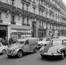Pariser Bilder [The street life of Paris]  Traffic on the Avenue de l'Opera Date: 1965 Location: France, Paris Keywords: cars, buildings, street sculptures, shops