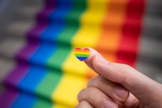 Heart shaped rainbow sticker in a hand for pride month celebration