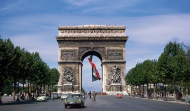 The Arc de Triomphe, summer 1963, with a huge French flag flying underneath it. Holiday in France. Vacances en France