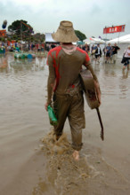 A musician walks through the flood water at the Glastonbury festival