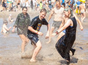 Young people playing in mud pool during 21th Woodstock Festival Poland