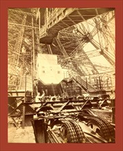 Eiffel Tower machinery with a man beside the wheel that raises elevator, during the Paris