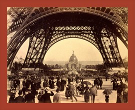 Crowd of people walking under the base of Eiffel Tower, view toward the Central Dome, Paris