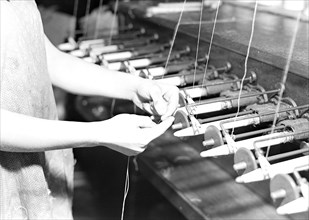Paterson, New Jersey - Textiles. Quiller tying the broken ends of thread being wound on to quills,