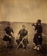 Two French officers, seated, and Zouave, standing with arm resting on rifle, Crimean War,