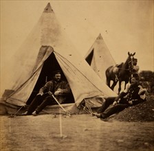 Officer of the 57th Regiment sitting with a sword across his lap at opening to his tent, another