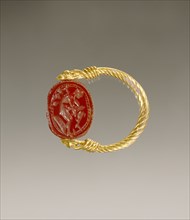 Gem Engraved with a Warrior Putting on Leg Armor; Etruria; 4th century B.C; Carnelian and gold; 0.8 × 1.4 × 1.1 cm