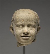 Head of a Child; Tarentum, Taras, South Italy; 300 - 200 B.C; Terracotta with clay slip; 13.5 × 11.5 cm, 5 5,16 × 4 1,2 in