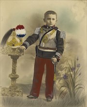 Boy in Military Dress with Helmet on Stand; E. Goubier, French, active 1890s - 1900s, 1899; Hand-colored gelatin silver print