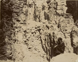 Man sitting at base of cliff wall; about 1860 - 1880; Tinted Albumen silver print