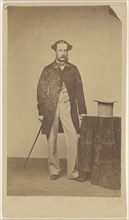 man with walking stick, standing near table with top hat; about 1865; Albumen silver print