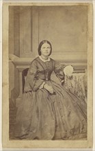woman holding small book, seated; 1865 - 1870; Albumen silver print
