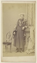 Asian man in robe wearing hat, standing; F. Schwarzschild, British, active Calcutta, India 1860s, 1860s; Albumen silver print