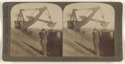 Gigantic steam shovel dumping 5-ton load of iron ore into car,  open-pit  mine, Hibbing, Minn; Underwood & Underwood, American