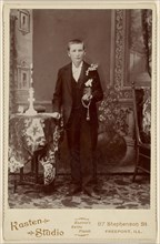 young man standing, holding book and beads; Kasten Studio; 1870 - 1880; Albumen silver print