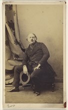 man with longish hair and mustache, seated on hassock, holding hat; Gustave Le Gray, French, 1820 - 1884, about 1865; Albumen
