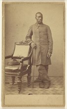 Black soldier standing near chair with hat in seat; Alexander Gardner, American, born Scotland, 1821 - 1882, about 1862
