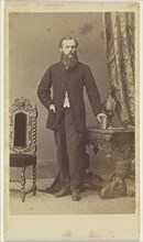 Full-bearded man, standing, with hand on book resting on table; Schwarzschild & Co; 1860s; Albumen silver print